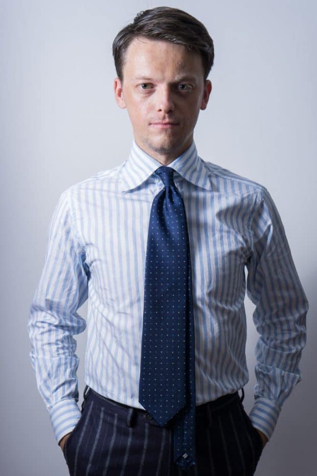 DeoVeritas logo with a professional businessman in a pinstripe suit at a corporate meeting or seminar setting.