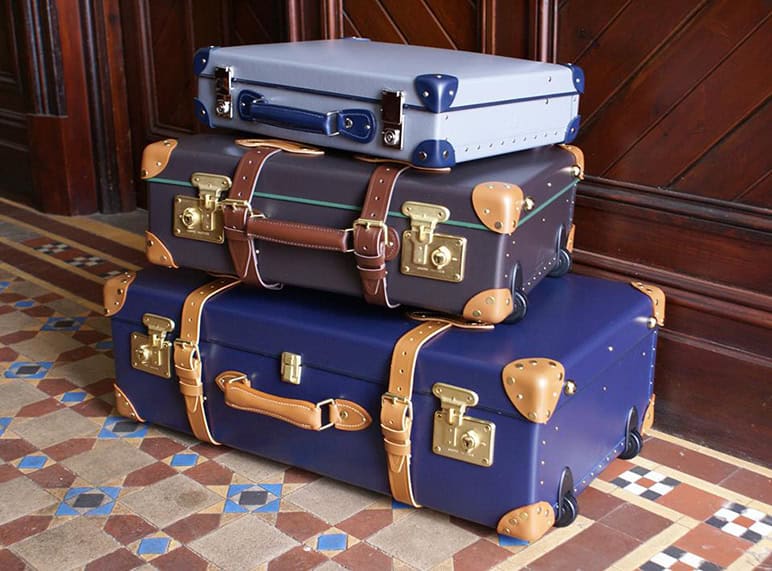 Vintage leather and fabric suitcases stacked for travel, featuring classic locks and handles, on a patterned tiled floor. Perfect for travel enthusiasts or vintage travel decor, showcasing durable, stylish luggage.