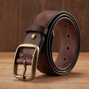 Brown leather belt with brass buckle on wooden surface, stylish men's fashion accessory.