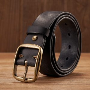 Black leather belt with antique brass buckle on wooden surface, stylish accessory for men and women, high-quality durable leather belt suitable for formal and casual wear.