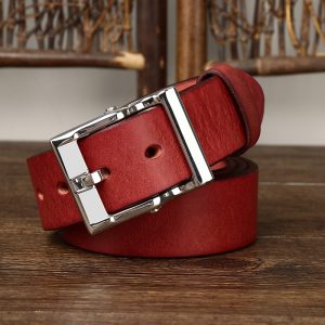 Red leather belt with a silver rectangular buckle displayed on a wooden surface.