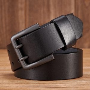 Black leather belt with metal buckle placed on wood surface.