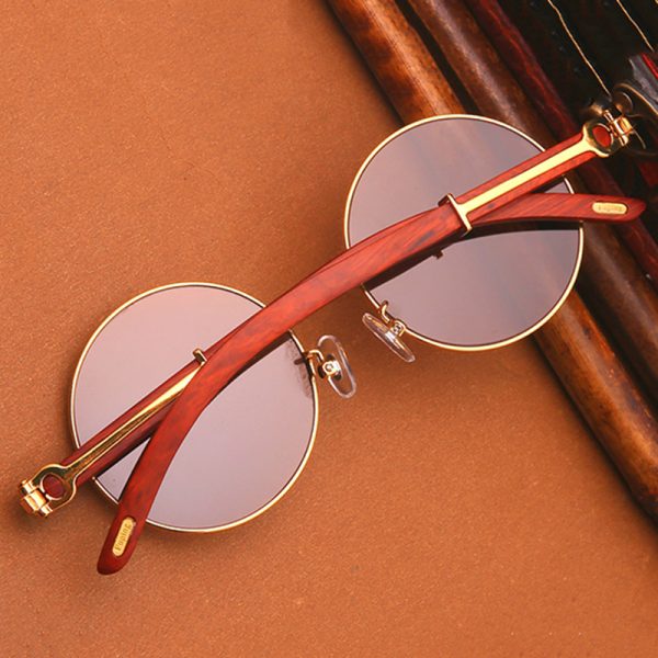 Vintage round sunglasses with wood and gold accents on a brown background.