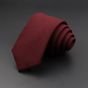 Soft burgundy men's dress tie neatly rolled on a dark grey background, perfect for formal occasions and professional attire.
