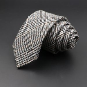A stylish black, white, and red checkered men’s tie with a classic pattern, rolled up on a dark background, perfect for formal or business attire.