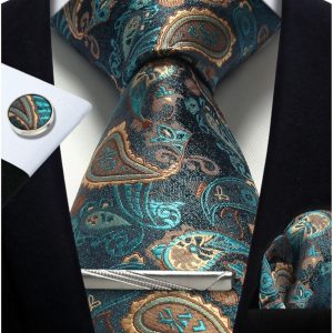 Elegant paisley patterned silk tie in shades of teal, gold, and black paired with a white dress shirt and black suit jacket for a sophisticated men's formal look.