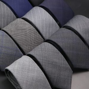 Elegant men's suits in various gray and navy tones with subtle plaid and pinstripe patterns, perfect for formal occasions and business attire. High-quality fabric and tailored fits exemplify sophisticated style.