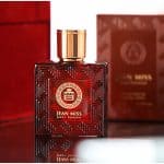Luxurious Jean Miss Pour Homme perfume bottle with intricate geometric design and gold accents, perfect for men's fragrance enthusiasts, placed on a reflective surface with elegant red packaging in the background.
