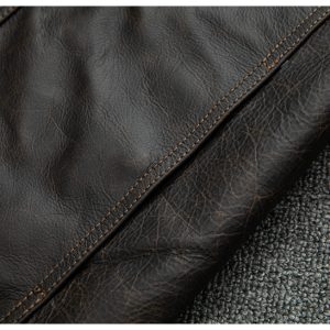 Luxurious dark brown leather upholstery with detailed stitching on a textured gray fabric background. High-quality material perfect for furniture, fashion accessories, or interior decor.