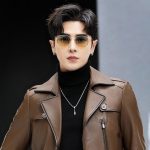 Stylish young man wearing sunglasses, leather jacket, and black turtleneck, showcasing modern fashion accessories and trendy urban style.