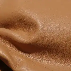 Luxury leather fabric close-up, high-quality textured brown leather material for fashion accessories or upholstery, detailed view of soft and durable leather texture for premium products.