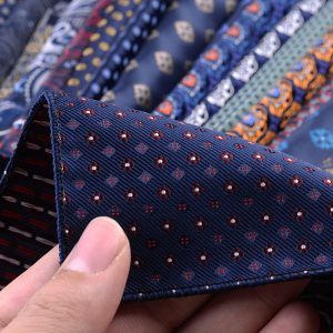 Vibrant navy blue men’s necktie with intricate red and white floral pattern, high-quality silk material, perfect for formal occasions and professional attire. Excellent craftsmanship for a sophisticated look.