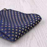Dark blue pocket square with gold floral pattern, perfect for formal occasions and elegant styling.
