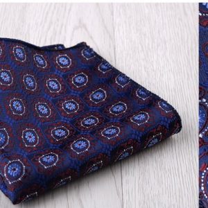 Vivid blue and red patterned fabric folded neatly on a light wooden surface, showcasing intricate floral motifs perfect for high-end fashion or home decor projects.