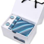Elegant men's gift set including a striped blue tie, matching cufflinks, and a pocket square in a sleek white presentation box, perfect for formal occasions and stylish accessories.