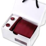 Elegant men's gift set featuring a burgundy textured tie, cufflinks, and a pocket square in a sleek white presentation box, ideal for formal occasions and stylish accessories.