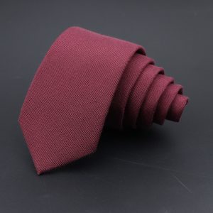 Elegant maroon necktie folded on black background for stylish formal wear, perfect for professional or special occasions.