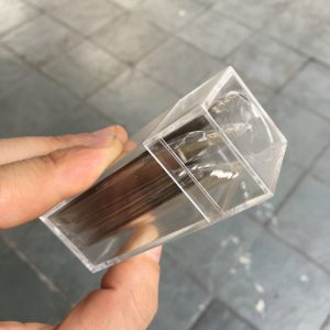 Acrylic perfume bottle inside clear plastic case, luxury fragrance packaging for men and women, elegant and modern design for high-end perfumes.