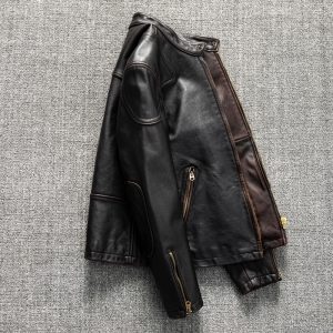 Black leather biker jacket with zippered pockets on a gray textured background.
